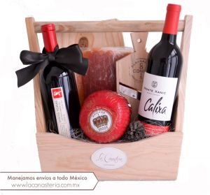Elegante arcón navideño con productos gourmet y dos botellas de vino tinto para una excelente degustación